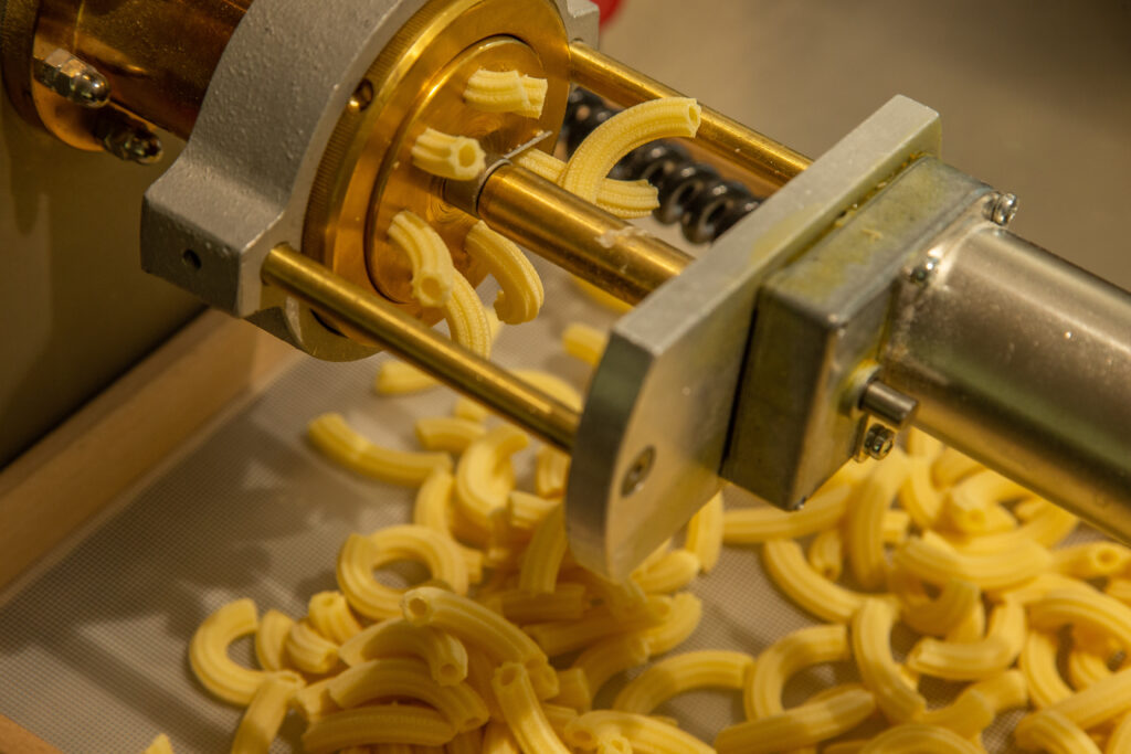 Fresh extruded pasta coming through a pasta extruder