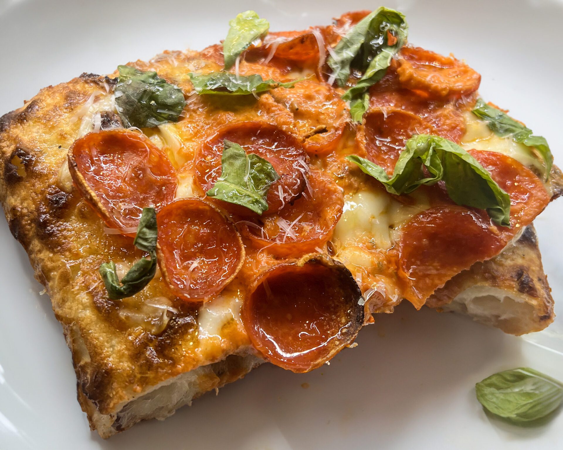 Slice of pizza with vodka sauce, pepperoni, and basil